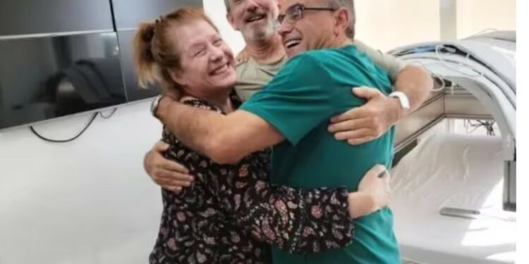 O paciente Scott Miller e a esposa Marianne Miller abraçam o médico brasileiro Marc Abreu. O tratamento desenvolvido por ele fez o câncer de próstata em estágio avançado entrar em remissão total - Foto: Divulgação/btt Corp.